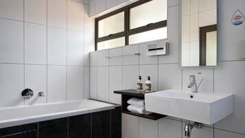 Une salle de bain moderne avec une baignoire, un lavabo et un miroir.