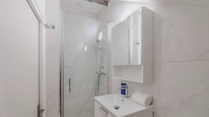 Ein Badezimmer mit Duschkabine aus Glas, einem weißen Waschbecken und einer Toilette.