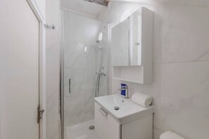 A bathroom with a glass shower enclosure, a white sink, and a toilet. - Charming studio - 2P- le Marais (Paris)