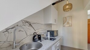 Eine Küche mit Marmor-Spritzschutz, einem Spülbecken, einem Wasserkocher, einem Toaster, einer Mikrowelle und einer Waschmaschine.
