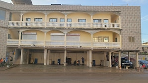 A multi-story building with balconies, a ground-level entrance, and a sign indicating a business. - BEL APPARTEMENT 1-Likouala! A stone's throw from downtown (LIBREVILLE)
