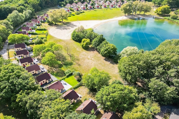An aerial view of a residential area with houses, a lake, and a grassy area.