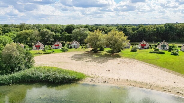 A rural landscape with houses, a pond, and trees.