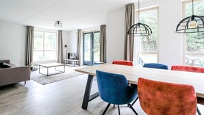 Uma sala de estar moderna com um sofá, uma mesa de jantar com cadeiras e uma televisão.