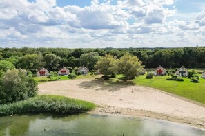 Ländliche Landschaft mit Häusern, einem Teich und blauem Himmel.