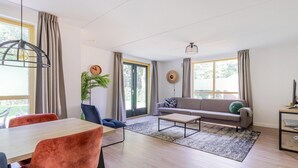 A modern living room with a sofa, coffee table, and dining area. - Serene Ewijk Abode by the Lake (Ewijk)
