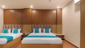Hotellihuone, jossa on kaksi sänkyä, seinissä puupanelointi ja lattialla puulattia.