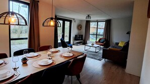 A dining area with a table set for four, a sofa, a TV, and a fireplace.