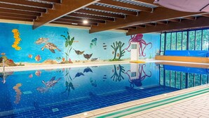 An indoor swimming pool with a mural of marine life on the walls.