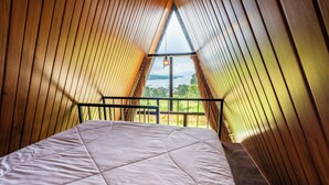 A bedroom with a bed, wooden sloped ceiling, and a window with a view. - Royal VIP Glamping Kintamani (Kintamani)