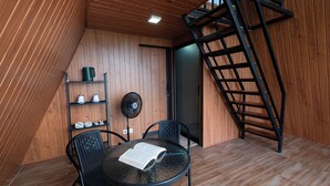 A small room with a round table, two chairs, a fan, a ladder, and a shelf with items. - Royal VIP Glamping Kintamani (Kintamani)