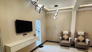 A modern living room with a flat-screen TV, two sofas, and pendant lighting. - Hariaaksh stay is a luxurious yet affordable home stay. (Varanasi)