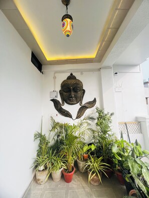 Ein Zimmer mit Buddha-Statue, Deckenleuchten und Topfpflanzen.