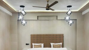 Un dormitorio con una cama, un ventilador de techo y luces colgantes.