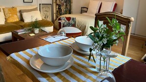 Une pièce comprenant un lit, un canapé, une table à manger avec des bols et un vase, ainsi qu’une chaise.