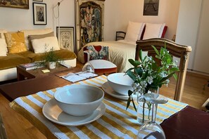 Una stanza con un letto, un divano, un tavolo da pranzo con ciotole e un vaso, e una sedia.