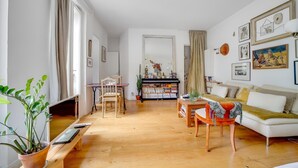 Un salon comprenant un canapé, une table basse, un téléviseur et une bibliothèque.