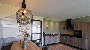 Una cocina moderna con armarios de madera, horno empotrado y comedor con mesa y sillas de madera.