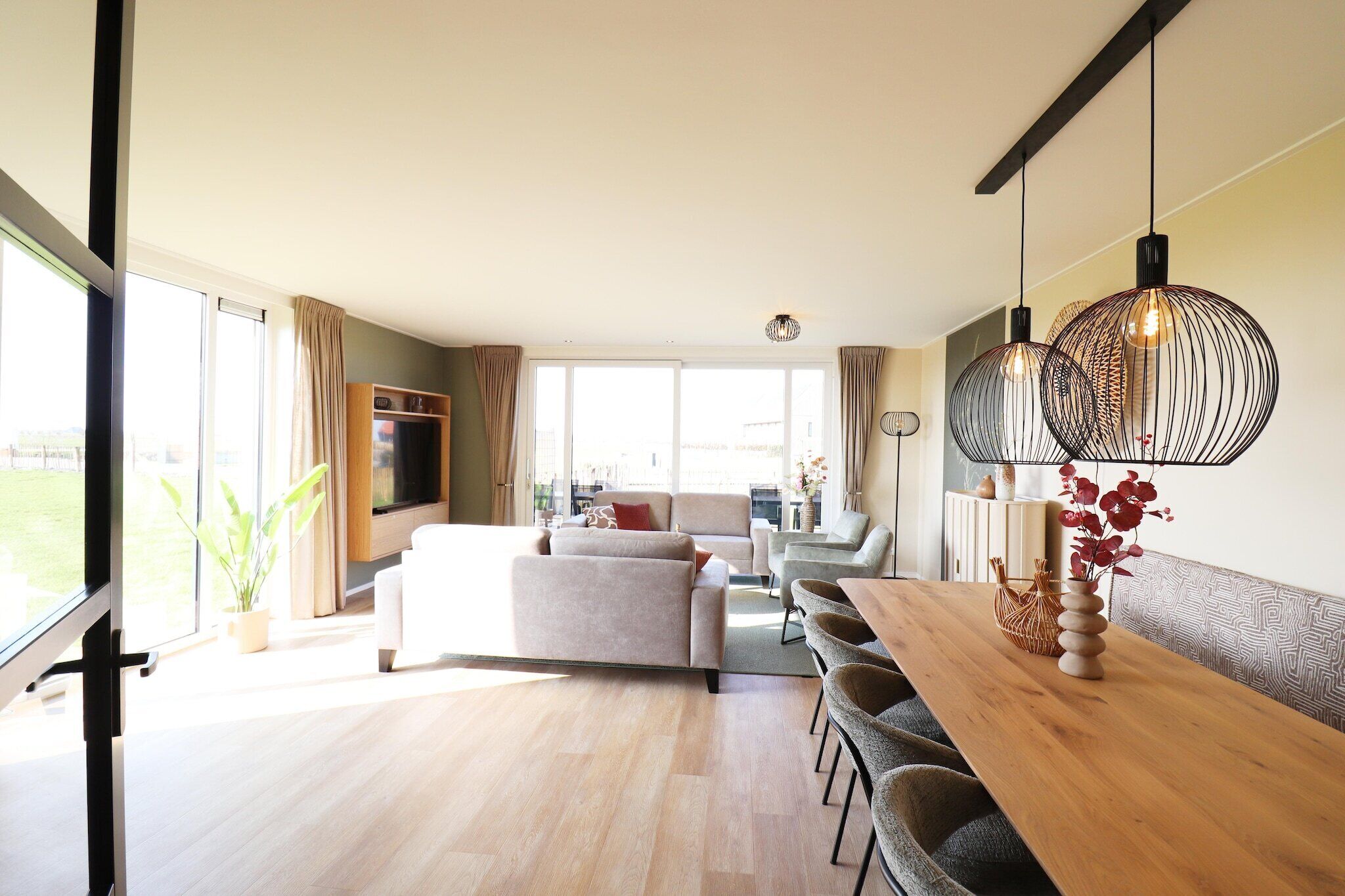 Un vaste espace de vie comprenant une table à manger, des canapés et une grande fenêtre offrant une vue sur l’extérieur.