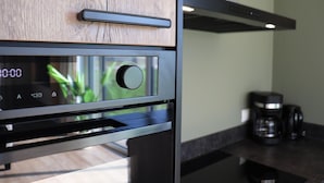 A modern kitchen with a built-in oven, a coffee maker, and wooden cabinetry. - Luxury waterfront villa (leons)