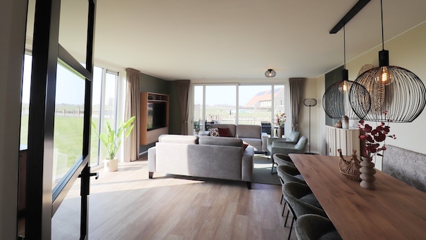 A spacious living area with a sofa, dining table, and chairs, large windows, and a view of the outdoors. - Luxury waterfront villa (leons)