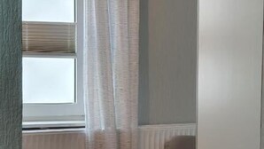 A small room with a window, a radiator, a round table with a plate, and a chair. - Seemoi (Norderney)