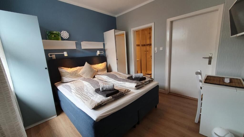 A bedroom with a bed, bedside tables, a wardrobe, and a door.