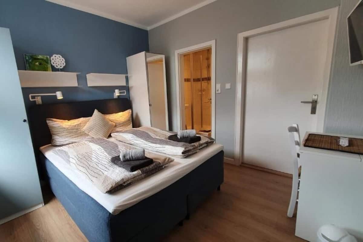 A bedroom with a bed, bedside tables, a wardrobe, and a door.