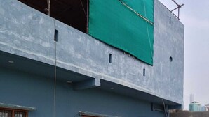 Un edificio de varios pisos con fachada azul, antenas parabólicas y un lomo cubierto con una lona verde.
