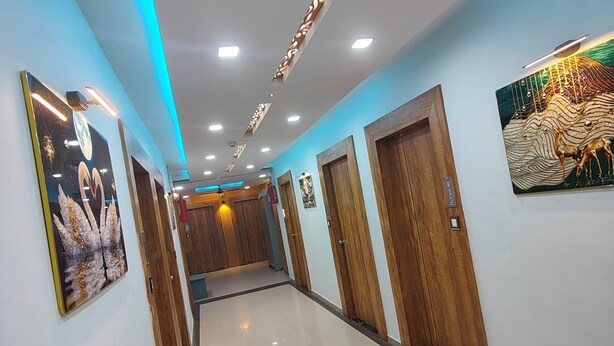 Un couloir d’hôtel avec un comptoir de réception, des portes en bois et un canapé à motifs.