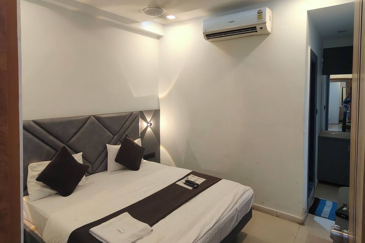 Une chambre d’hôtel moderne équipée d’un lit, d’un climatiseur et d’un luminaire au plafond.