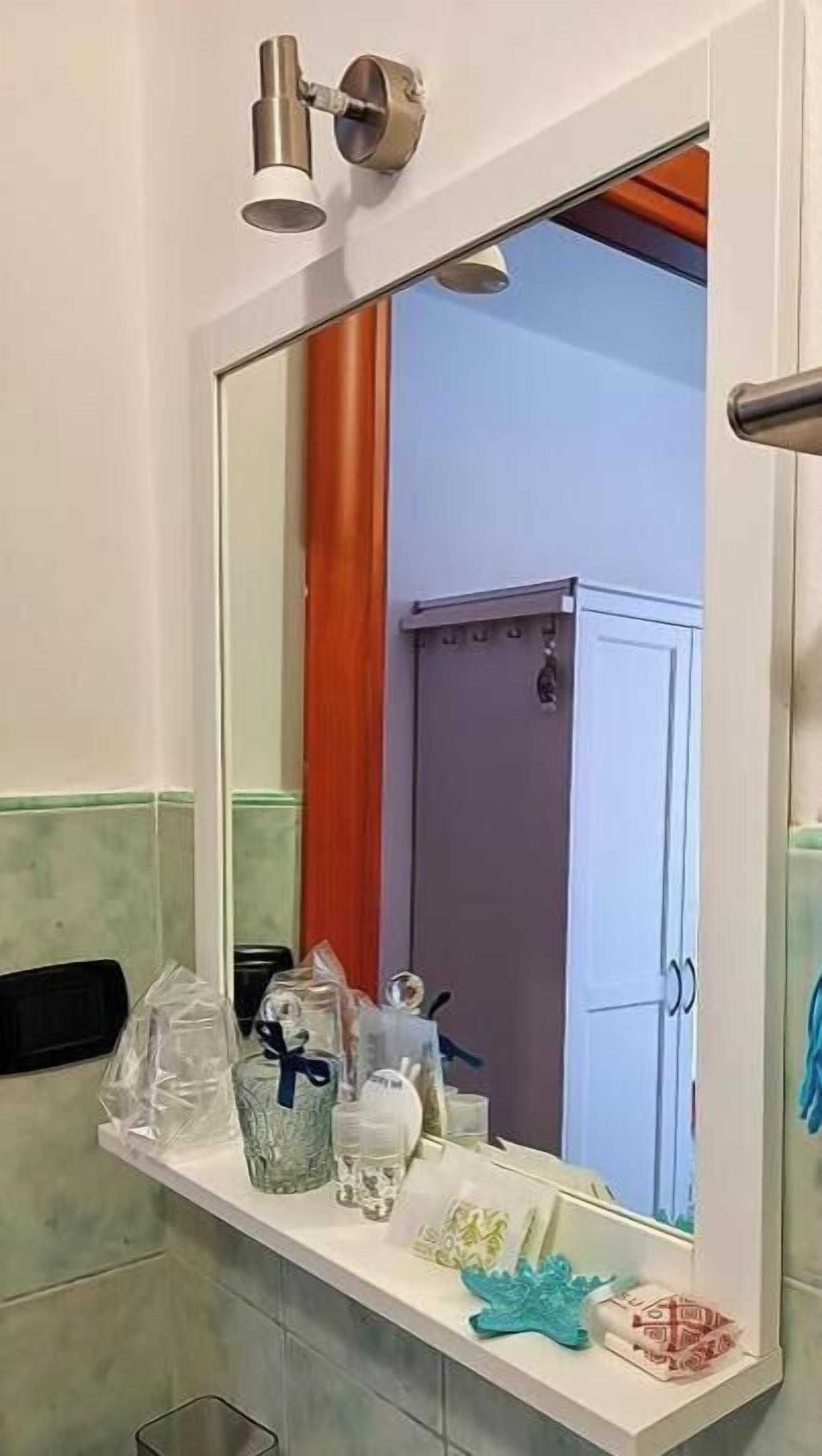 A bathroom with a mirror, a towel rack with a blue towel, and toiletries on the counter.