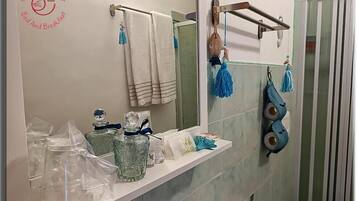 Un baño con espejo, toallero y artículos de aseo en la encimera.