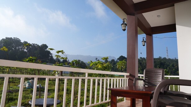 Un balcon donnant sur un paysage verdoyant et des montagnes.