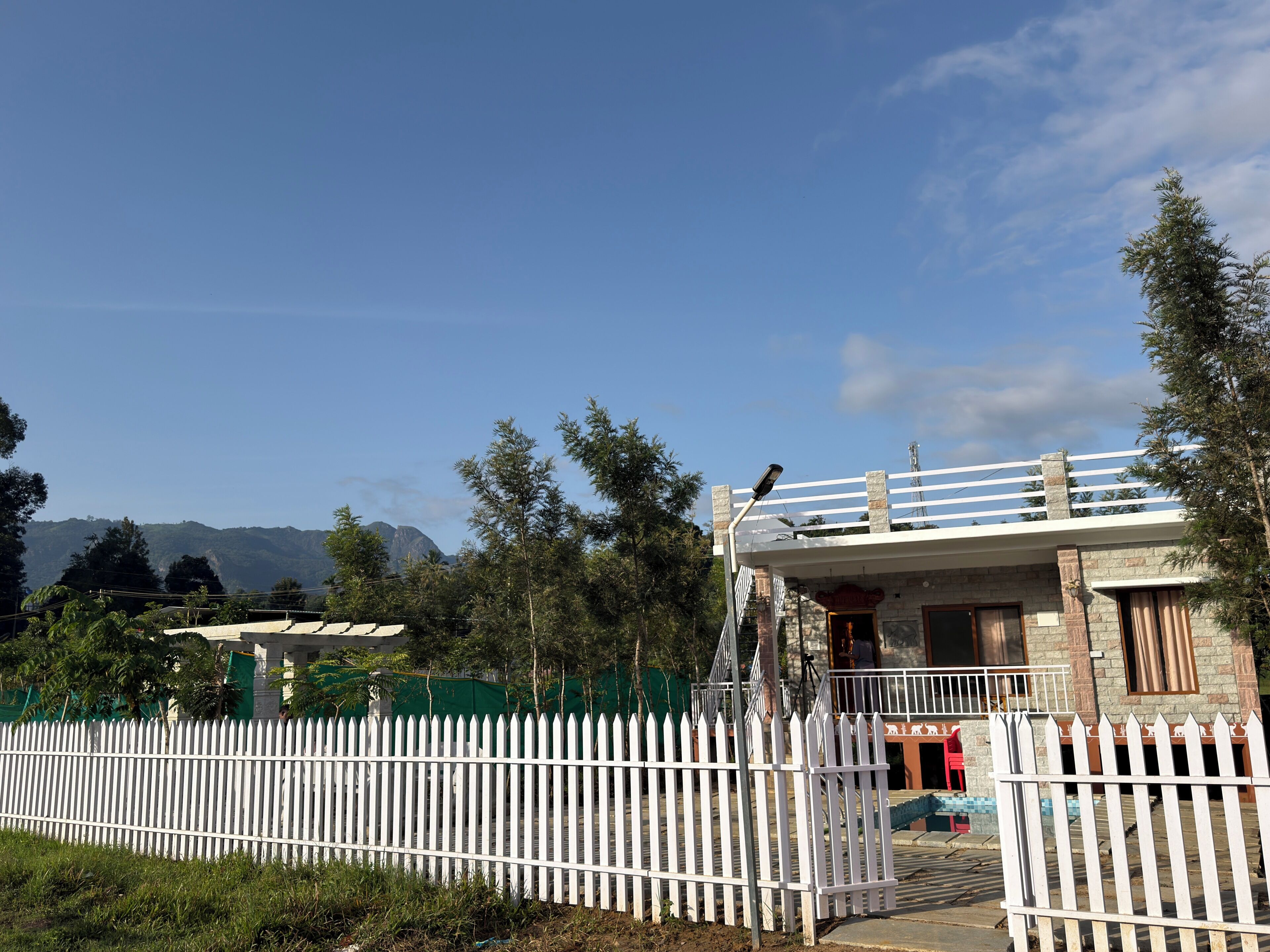 A building with a white picket fence, a balcony, and a mountain backdrop.