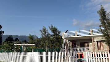 A building with a white picket fence, a balcony, and a mountain backdrop.
