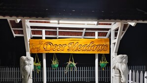 Une enseigne en bois portant l’inscription « Deer Meadows » est suspendue sous une structure blanche soutenue par des piliers en pierre.