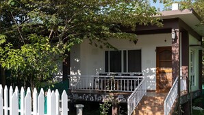 Une maison avec un porche à l’avant, un escalier et une clôture en bois peinte en blanc.