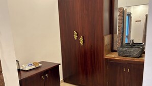 Une armoire en bois avec des poignées en laiton, une petite table avec un plateau et un évier en pierre.
