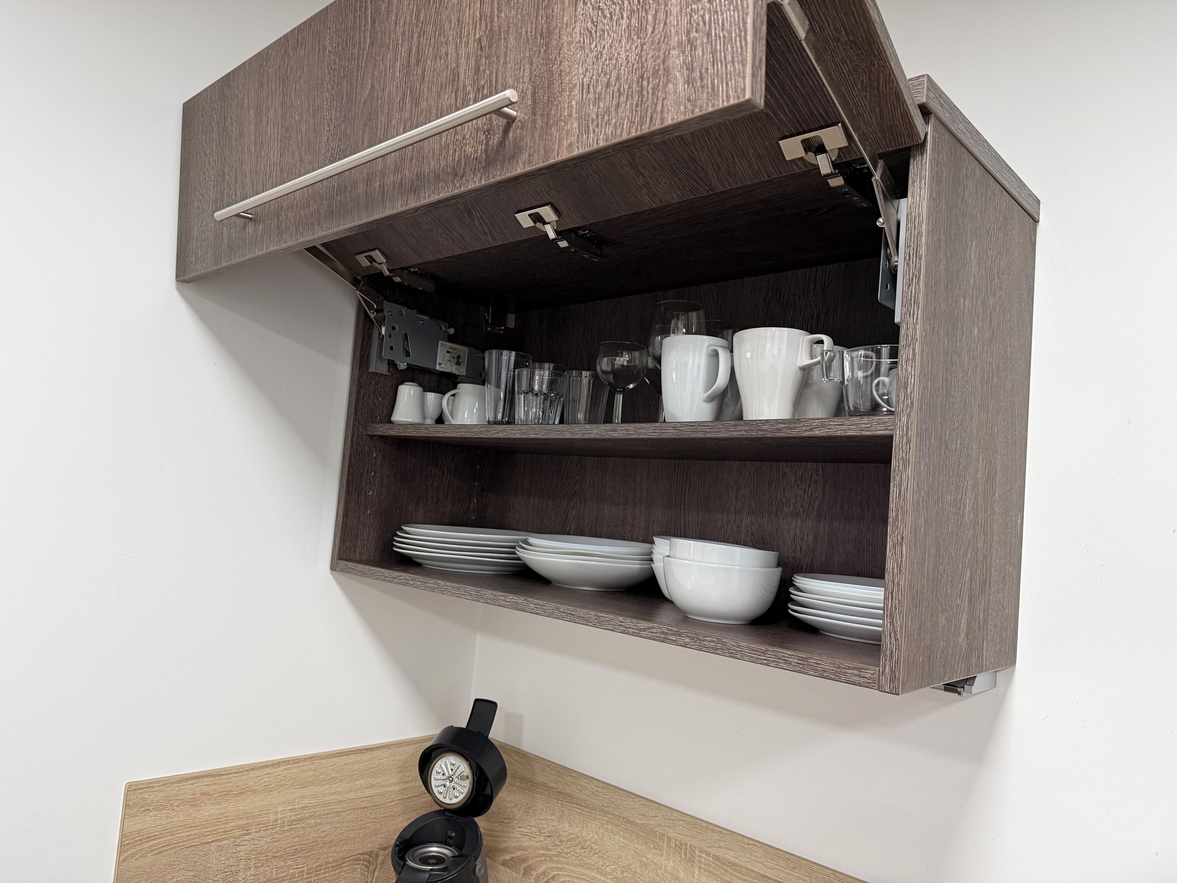 Eine Küche mit Holzschränken, einer Kaffeemaschine und weißen Geschirr.