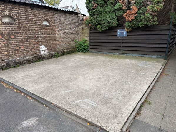 A paved area with a brick wall and a wooden fence.