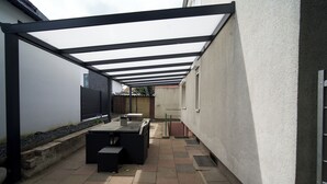 A covered patio area with outdoor furniture, a pergola, and a wall-mounted table. - Spacious, Comfortable Apartments in a Quiet Setting Near Cologne (Pulheim)