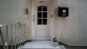 A white door with a keypad lock, a small mailbox, and a flower pot on the steps. - Spacious, Comfortable Apartments in a Quiet Setting Near Cologne (Pulheim)