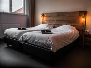 A double bed with a wooden headboard and two bedside lamps.