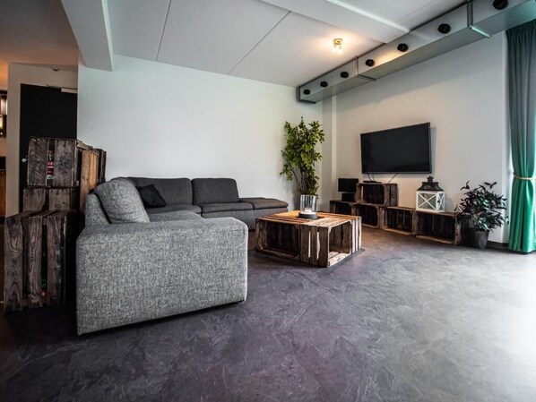 Una sala moderna con un sofá seccional, una mesa de centro, un televisor de pantalla plana y una planta.