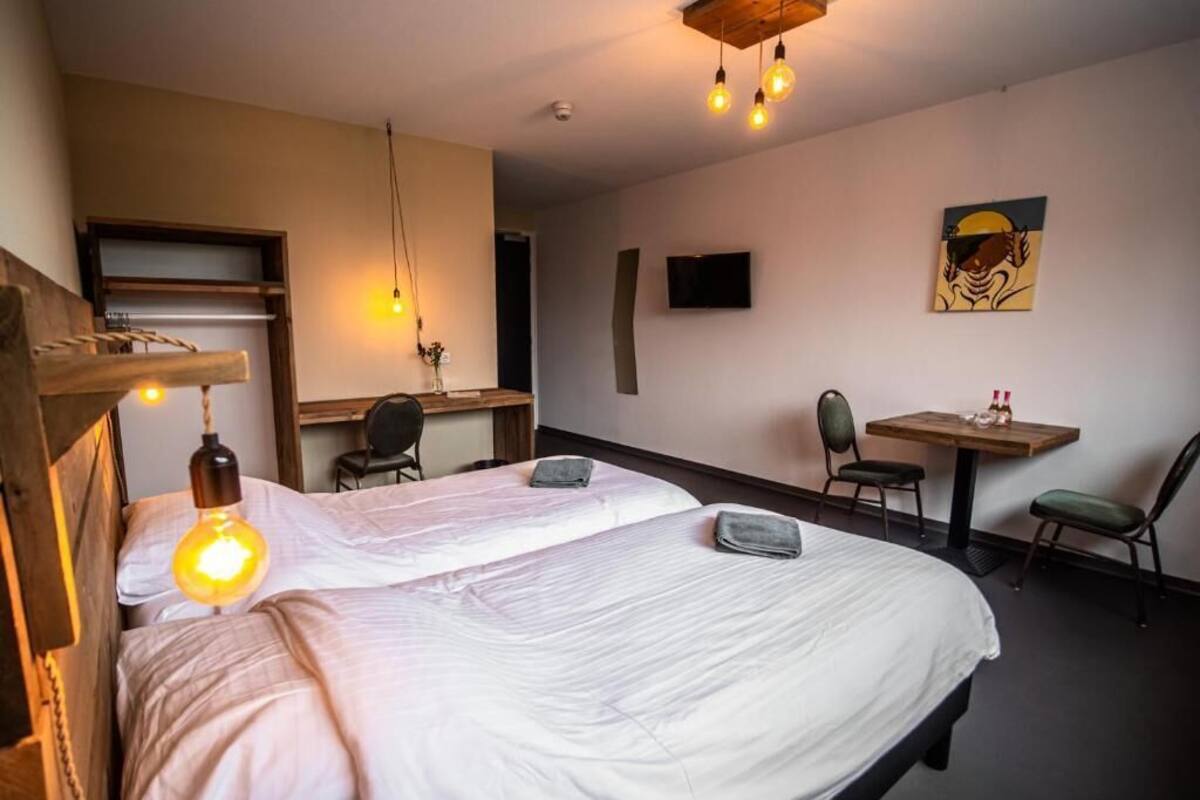 A bedroom with a bed, bedside tables, a desk, a chair, and a television.