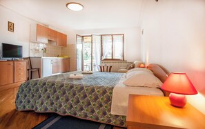 Ein Schlafzimmer mit Bett, Nachttischlampe und Blick auf die Küche.