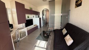 Een moderne woonruimte met keuken, een eethoek en een zithoek met een bank.