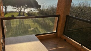 Een balkon met een tafel en stoelen, met uitzicht op een waterpartij en bomen.