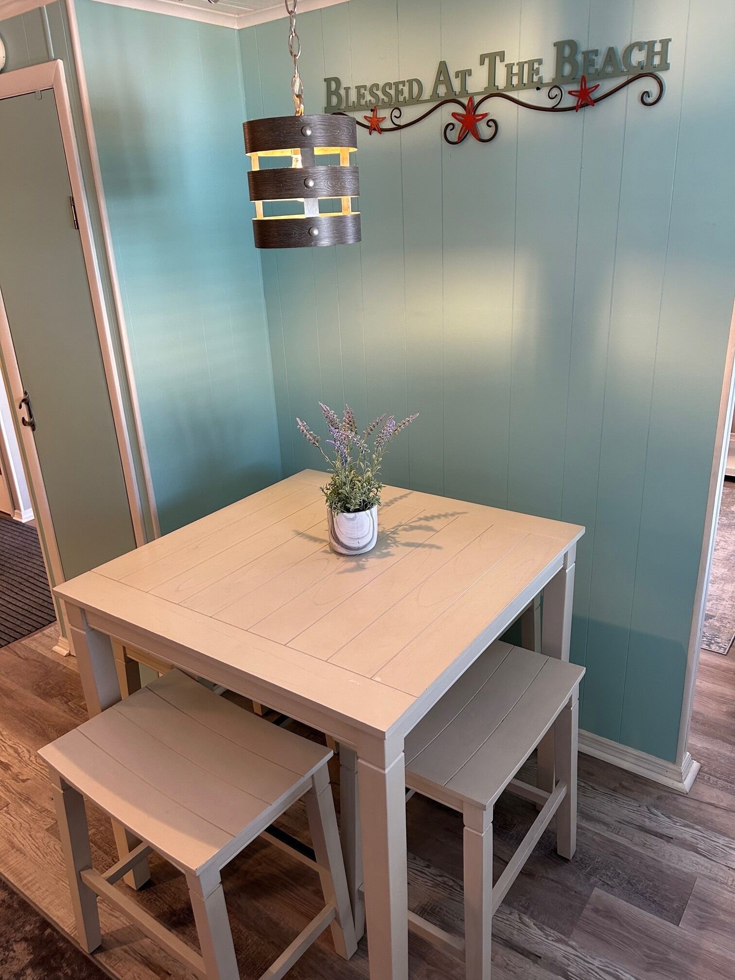 Un espace repas avec une table et des bancs, un luminaire suspendu et un panneau mural.